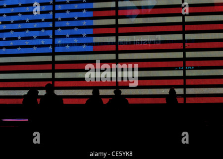 Menschen, die Silhouette vor einer großen amerikanischen Flagge angezeigt auf einer Videowand im Times Square in New York City, USA Stockfoto