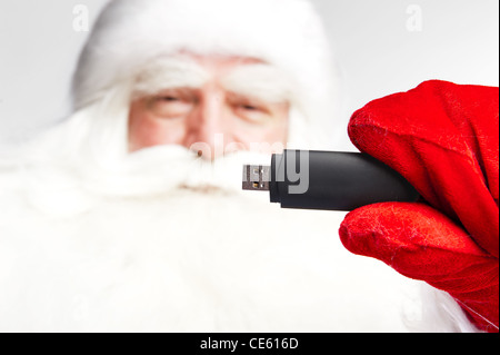 Traditionellen Weihnachtsmann hält 3g USB-Modem im Arm im Vordergrund. Isoliert auf weiss. Stockfoto