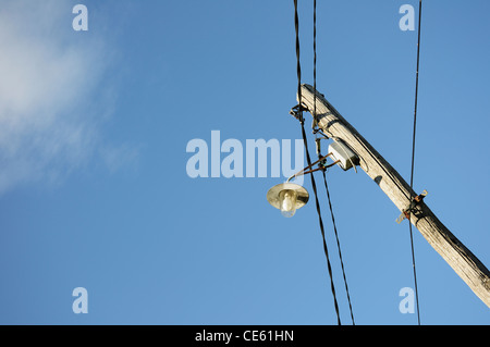 Power-Pylon mit und Straßenlaterne gegen blauen Himmel Stockfoto