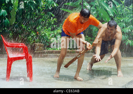 Indische Teenager Jungen spielen Cricket in Monsun regen ; Bombay ; Mumbai ; Indien ; Asien ; MR#413 Stockfoto