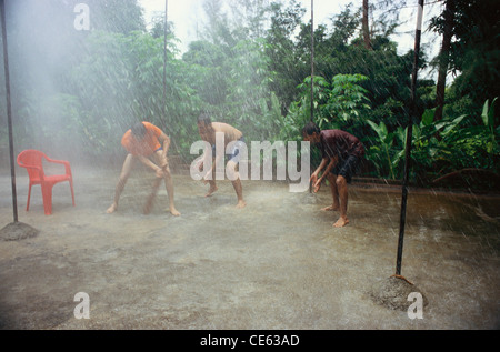 Indische Teenager Jungen spielen Cricket in Monsun regen ; Bombay ; Mumbai ; Indien ; Asien ; MR#413 Stockfoto