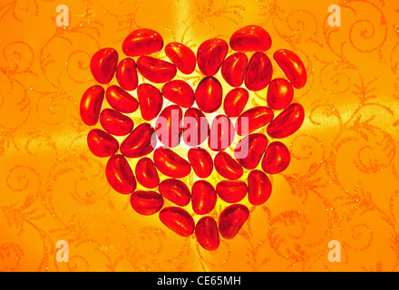 Das rote Leuchten Herz aus Glas auf einem gelben durchbrochenen Hintergrund Stockfoto