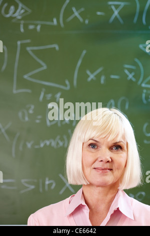 Porträt von Reife blonde weibliche Blick in die Kamera von Blackboard auf Hintergrund Stockfoto