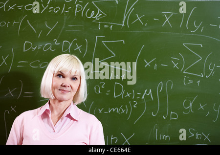 Porträt von Reife blonde weibliche Blick in die Kamera von Blackboard auf Hintergrund Stockfoto