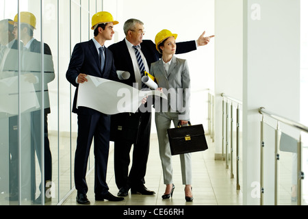 Drei Architekten stehen in Bürogebäude und Interaktion Stockfoto