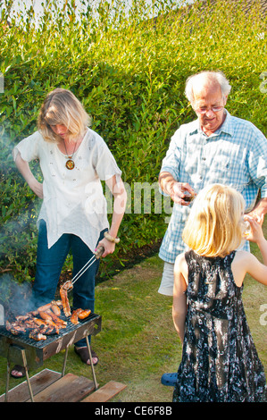 Familie Grill Garten Blackpool England uk Europa Kochen unter freiem Himmel Bbq Fleisch Rauch junge Frau smokey Rauch Augen Rauch in Augen Stockfoto