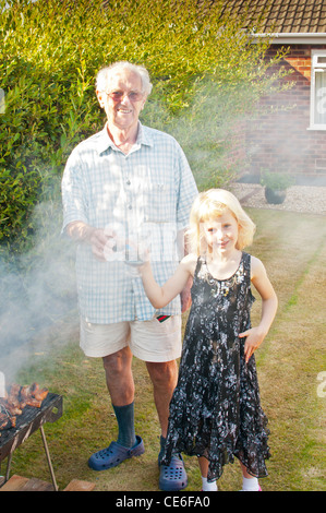 Familie Grill Garten Blackpool England uk Europa Kochen unter freiem Himmel Bbq Fleisch Rauch junge Frau smokey Rauch Augen Rauch in Augen Stockfoto