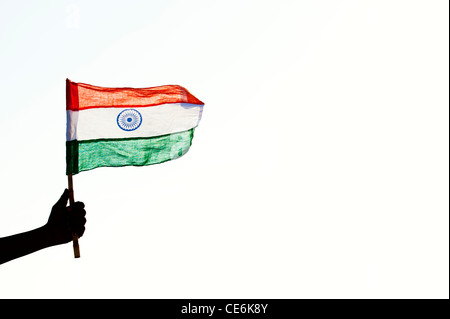 Indische mans Hände halten eine indische Flagge gegen einen hellen Hintergrund. Silhouette. Indien Stockfoto