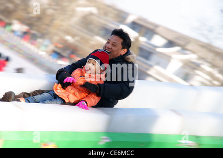 Vater und Sohn haben Spaß auf Eis Folie in Peking China Stockfoto