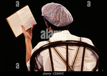 Mann auf Stuhl sitzend und Buch Stockfoto