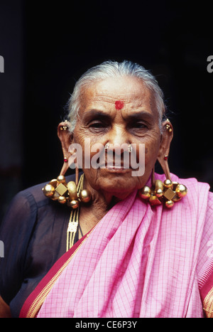 Alte südindische Frau trägt verschwindende traditionelle Thandatti Ohrringe massive große große große große Gold Ohrring Indien Asien Stockfoto