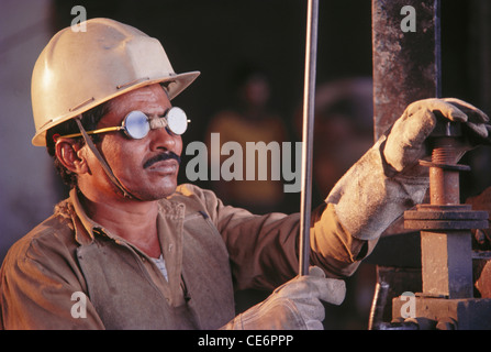 Mann arbeitet in der Fabrik tragen Helm und Brille; Indien Stockfoto
