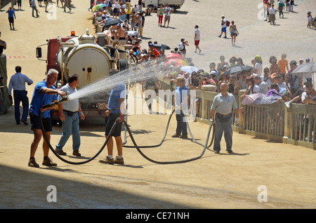 Stadtwasser Mitarbeiter versprühen die Piazza del Campo vor dem Pferd Rennen am Tag Palio di Siena, Siena, Toskana, Italien Stockfoto