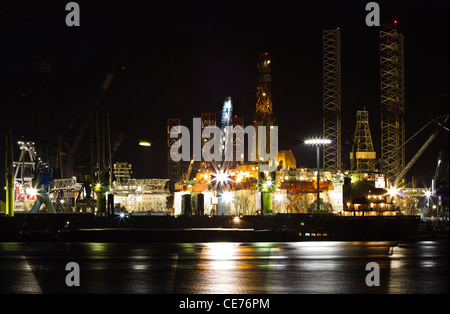 Schiffsreparatur und Dock in der Nacht - Industrie, Schiffe im Vordergrund und Bohrplattformen im Hintergrund Stockfoto