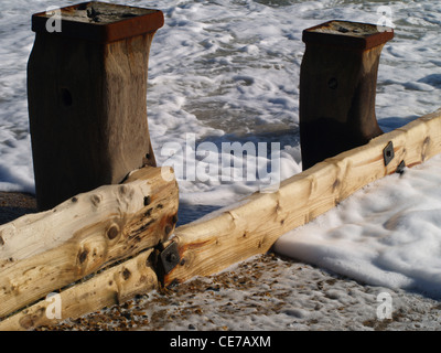 Zwei Wellenbrecher Beiträge von wellenbrecher Holz am Rand der Gezeiten auf der englischen Südküste steinigen Strand verbunden Stockfoto