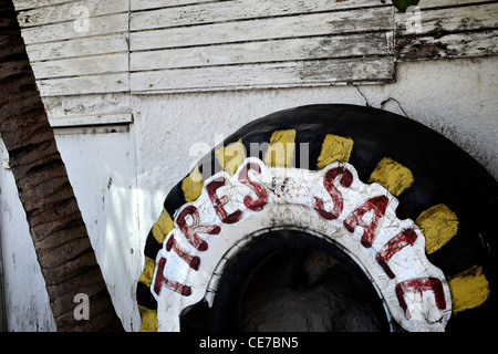 Reifen an der weißen Wand angelehnt. Kommerzielles Zeichen für einen kleinen Reifenverkauf in Saint Martin, Karibik. Stockfoto