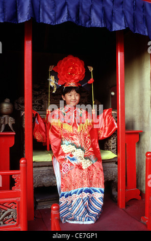 Das junge chinesische Mädchen trägt ein gemietetes Hochzeitskleid im Stil der Qing-Dynastie, während es den Tiantan Park in Peking besucht Stockfoto