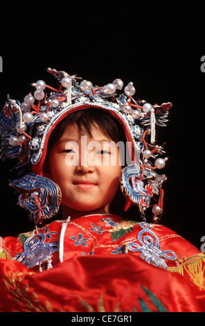 Das junge chinesische Mädchen trägt ein gemietetes Hochzeitskleid im Stil der Qing-Dynastie, während es den Tiantan Park in Peking besucht Stockfoto