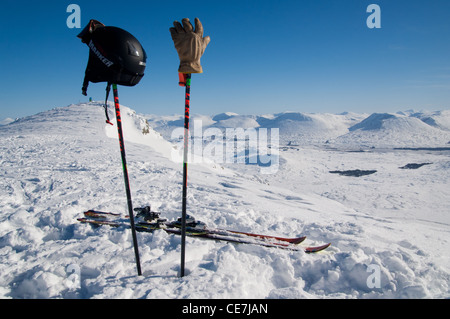 Skistöcke klemmt im Schnee mit Handschuhen und Helm auf der Oberseite fest mit einem Blick von oben von Glencoe Ski Resort im hellen Sonnenschein und tiefen Schnee Stockfoto