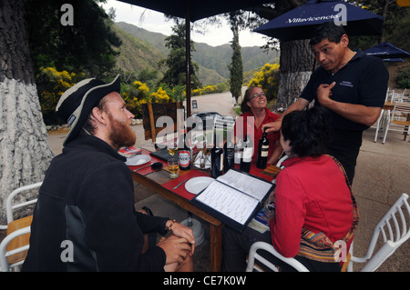 Kellner und Touristen über den Wein und Speisekarte bei Villavicencio, Argentinien. Weder Herr PR Stockfoto