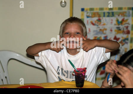 Kleiner Junge am Tisch Grimassen. Stockfoto