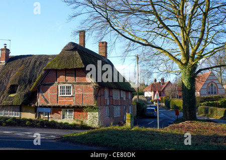 Alten strohgedeckten Hütte und Land Lane in der Ortschaft Pitt in der Nähe von Winchester, Hampshire, England. Beachten Sie die schlechten Zustand von Stroh. Stockfoto