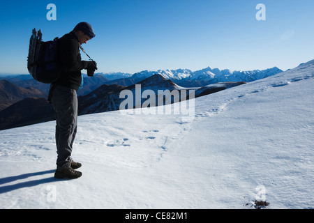 Mann mit Blick auf seine Digitalkamera, Pic De La Calabasse (2210 m), in der Nähe von Saint-Lary, zahlt Couserans, Ariege, Pyrenäen, Frankreich. Stockfoto