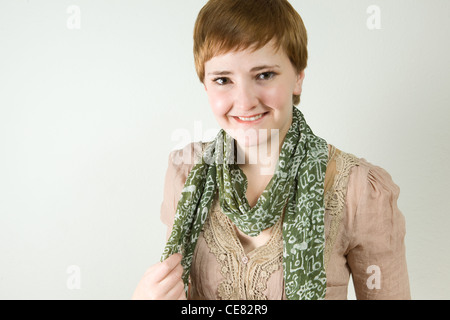 Studioportrait lächelnder junge rothaarige Frau tragen hübsche Spitzenbluse und grünen Schal. Stockfoto