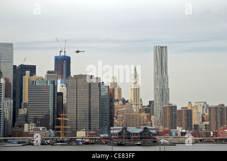 Ein Hubschrauber fliegt über South Street Seaport und Manhattan Wolkenkratzer aus Brooklyn Heights Promenade betrachtet. Stockfoto