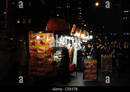 Nacht-Ansicht Menschen den Kauf zwei Halal Fastfood-Ständen elektrisches Licht Imbisswagen, West 50th Street, in der Nähe von 6th Avenue, New York Stockfoto