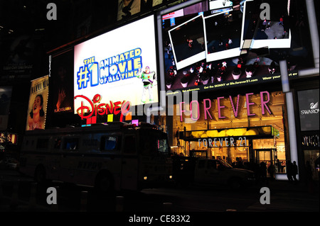 Nacht-Ansicht Menschen zu Fuß, Bus bewegte Vergangenheit, Neon Fassaden Forever 21 Kleidung Boutique, Disney Store, 7th Avenue, New York Stockfoto