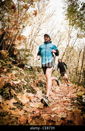 Zwei Männer Trail-running-durch einen Wald in den Farben des Herbstes. Stockfoto