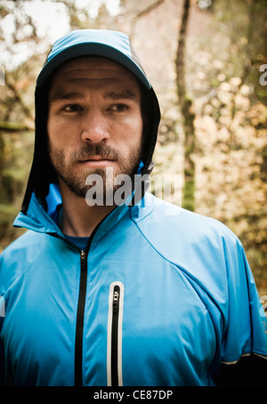 Porträt eines bärtigen jungen Mannes tragen eine Kapuze Laufjacke. Stockfoto
