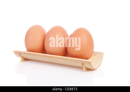 Drei Hühnereier hintereinander in hölzernen Halter auf weißem Hintergrund Stockfoto