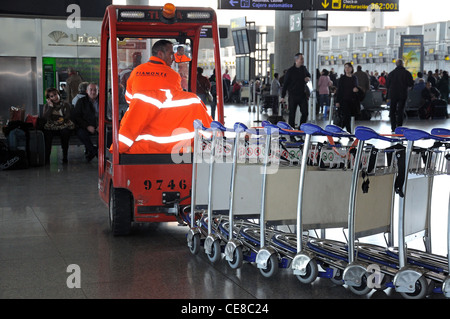 Arbeiter sammeln eine Reihe von Gepäckwagen im Terminal 3, Flughafen Malaga, Malaga, Provinz Malaga, Costa Del Sol, Spanien. Stockfoto