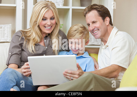 Eine attraktive glückliche, junge Familie Mutter, Vater und Sohn sitzen auf einem Sofa zu Hause verwenden einen Laptop-computer Stockfoto