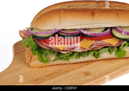 Nahaufnahme von Schinken und Käse sub Sandwich mit Salat Tomaten Zwiebeln und Gurke auf Holz deli Board auf weißem Hintergrund Stockfoto