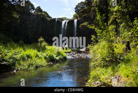 Ein paar stehen an der Basis der Whangarei Falls auf der Hatea River, Northland, Nordinsel, Neuseeland. Stockfoto