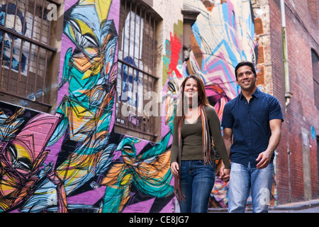 Junges Paar Hand in Hand und mit Blick auf die Gasse Straßenkunst. Hosier Lane, Melbourne, Victoria, Australien Stockfoto