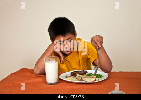 Willensstark hartnäckige 10-11 Jahre alten Hispanic junge am Tisch sitzen will nicht Herr © Myrleen Pearson zu essen Stockfoto