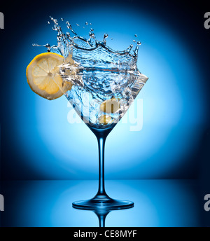 Splash Martini vor herumfliegenden Oliven. Objekt auf blauem Grund. Stockfoto