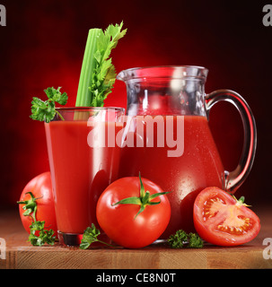 Stillleben: Tomaten, Krug und Glas voll frischer Tomaten Saft auf Holztisch. Stockfoto