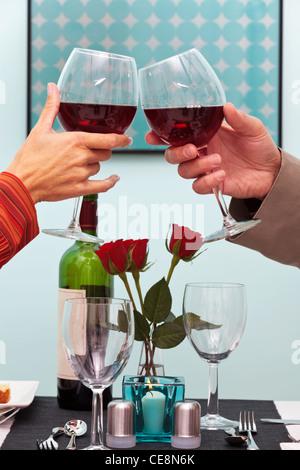 Foto von einem Paare Hände Toasten ihre Gläser Rotwein über den Tisch in einem restaurant Stockfoto