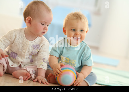 Zwei Babys auf dem Boden sitzend Stockfoto