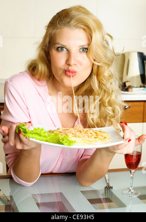 schöne junge Frau zu Hause in der Küche, Spaghetti-Essen Stockfoto