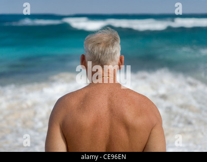 Ein senior Mann an den Strand blicken aufs Meer. Stockfoto