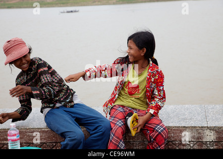 Zwei junge Mädchen spielen an einer Wand mit Blick auf die Tonie-Sap-Fluss. Eine spielerische und süße Komposition. Kambodscha, Phnom Penh. Stockfoto