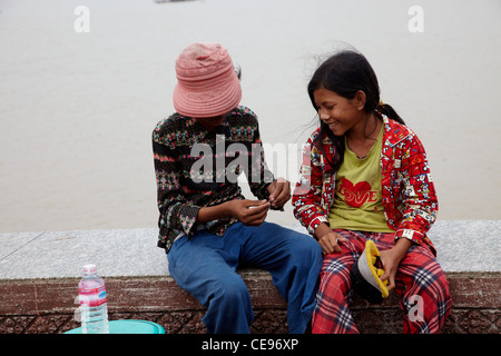 Kambodscha, Phnom Penh; Kinder saßen auf einer Wand zu spielen. Sie alte Lappen Kleidung zu tragen, haben wenig Geld aber viel gelacht. Stockfoto