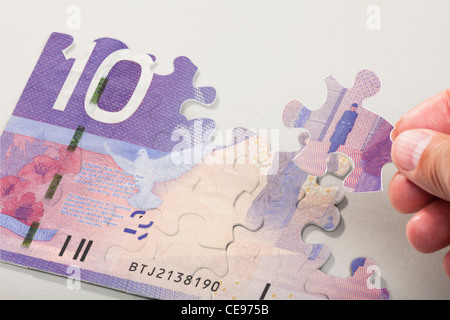 Männliche Hand anordnen Puzzleteile, die kanadische Währung zu schaffen Stockfoto