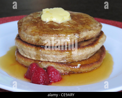 Einen leckeren Pfannkuchen mit Ahornsirup und Butter, mit Himbeeren auf der Seite.  Das Frühstück hat hohen Kaloriengehalt. Stockfoto